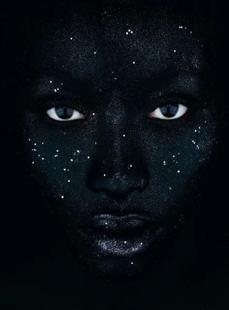 A face dusted with starlight, eyes open in the dark